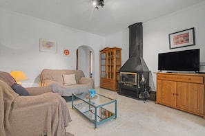 A living room with a sofa, a glass coffee table, a fireplace, a television, and a cabinet.