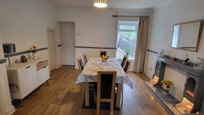 Ein Essbereich mit einem Marmortisch, Holzstühlen, einem weißen Schrank und einem Kamin.