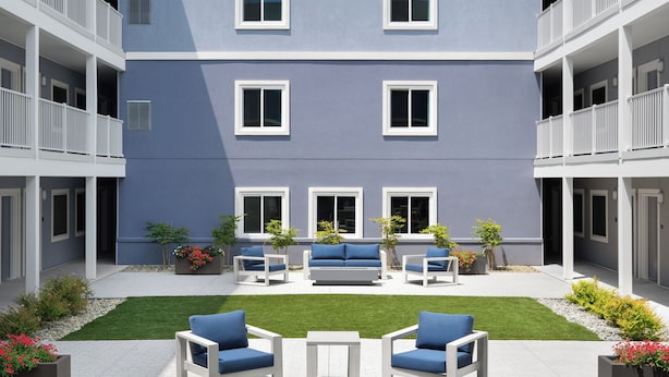 A multi-story building with balconies, a courtyard with seating, and a well-maintained lawn.