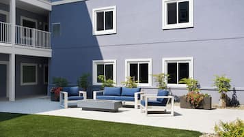A modern building with a courtyard, outdoor seating, and potted plants.