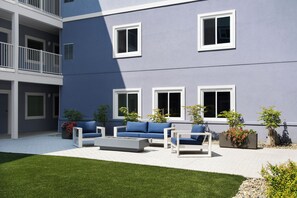 A modern building with a courtyard, outdoor seating, and potted plants.