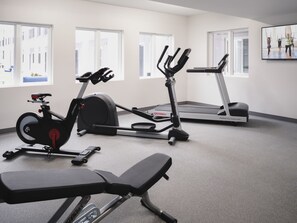 A gym with a stationary bike, elliptical, treadmill, and bench. - stayAPT Suites Hampton (Hampton)