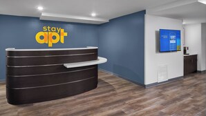 A reception desk with a dark finish, a blue wall, and a mounted screen displaying information.