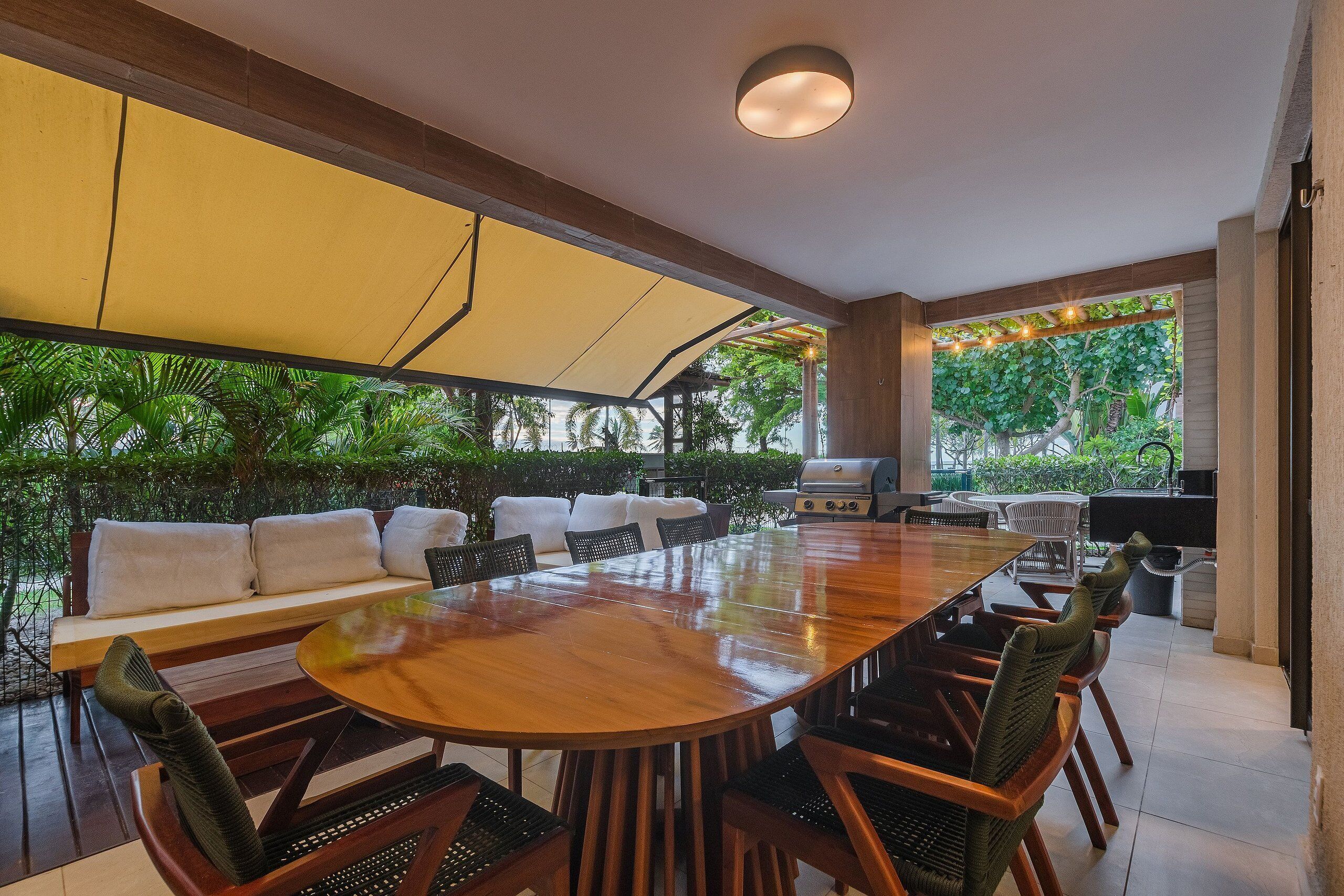 Un amplio espacio exterior con comedor, que incluye una gran mesa de madera, sillas y un sofá.