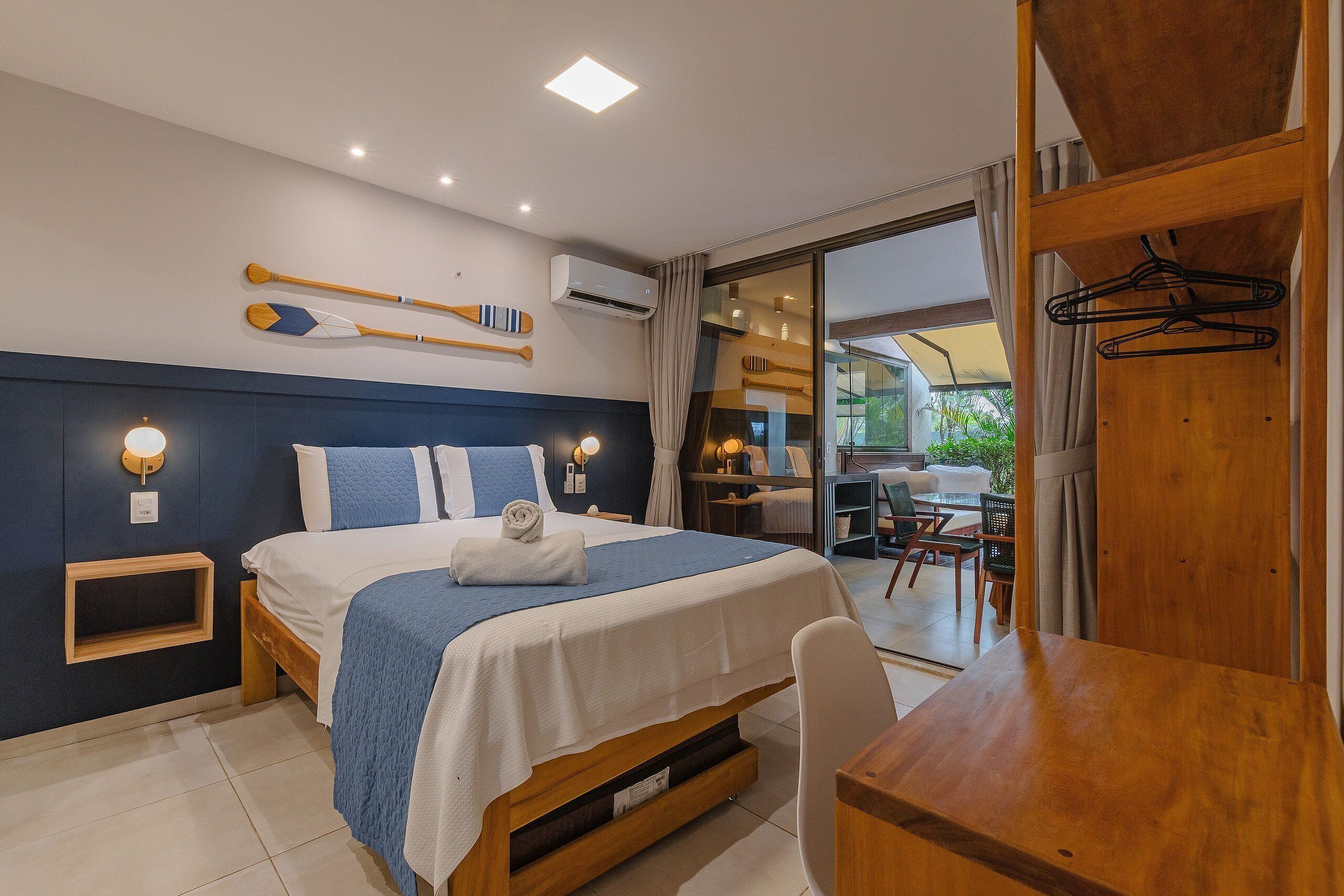 Un dormitorio con cama, mesitas de noche, un escritorio y vistas al exterior.