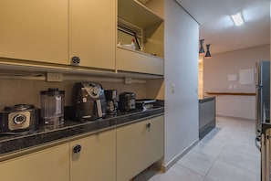 A kitchen with a black countertop, a coffee maker, a blender, and a toaster. There are cabinets above and below the counter. - Wai Wai Cumbuco Residence #c101 by Carpediem (Caucaia)