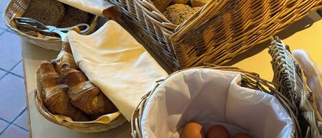 Un buffet de petit-déjeuner avec du pain, des croissants et des œufs, le tout présenté dans des paniers en osier.