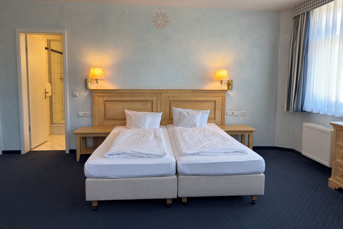 Un lit double avec deux tables de chevet, une tête de lit en bois et une lampe fixée au mur.