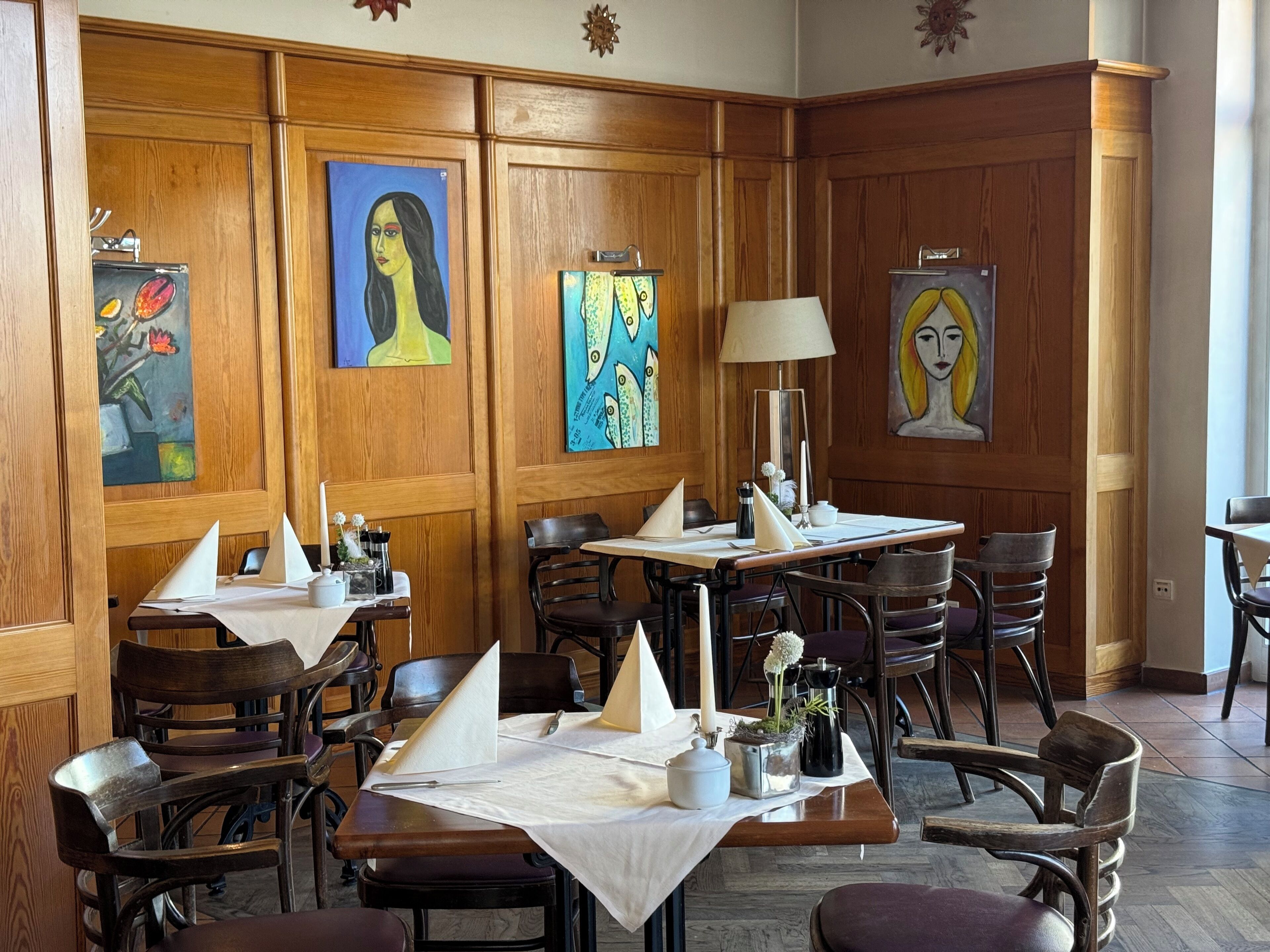 Un comedor con paneles de madera, mesas con manteles blancos y sillas.