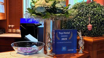 A reception desk with a vase of flowers, a framed award for 'Top Hotel Award 2025', and a decorative bunny figurine.