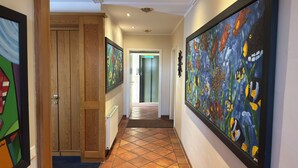 A hallway with wooden doors, tiled flooring, and artwork on the walls. - Strandhotel Sonnenburg by ANS (Kuehlungsborn)