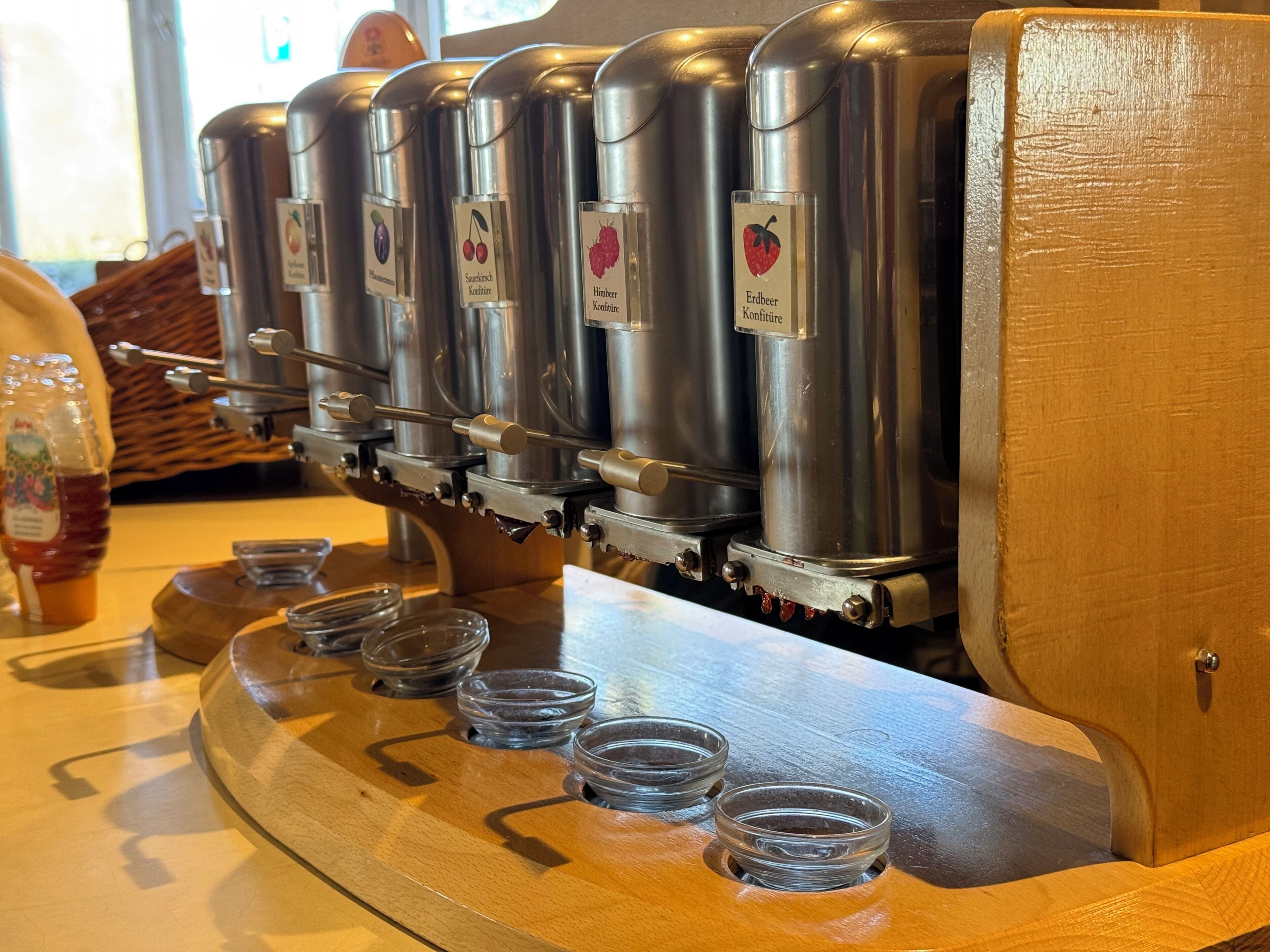 Une machine à café offrant différentes options de préparation, un comptoir en bois et des tasses en verre transparent.