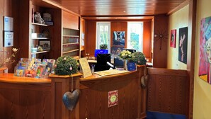 A reception desk with a computer, a plant, and a heart-shaped decoration. - Strandhotel Sonnenburg by ANS (Kuehlungsborn)