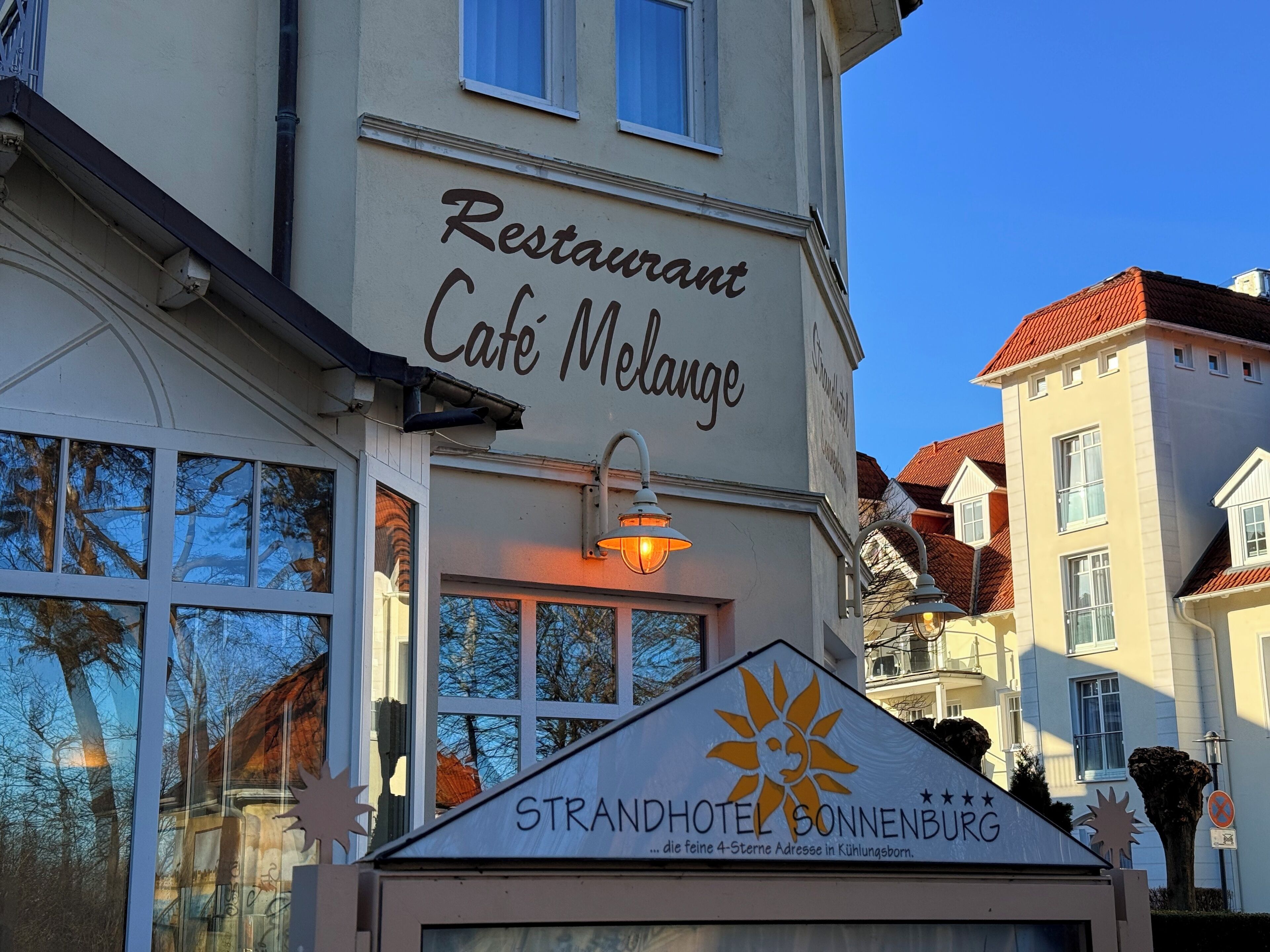 Un bâtiment avec une enseigne indiquant « Restaurant Café Melange » et une autre indiquant « Strandhotel Sonnenburg ».