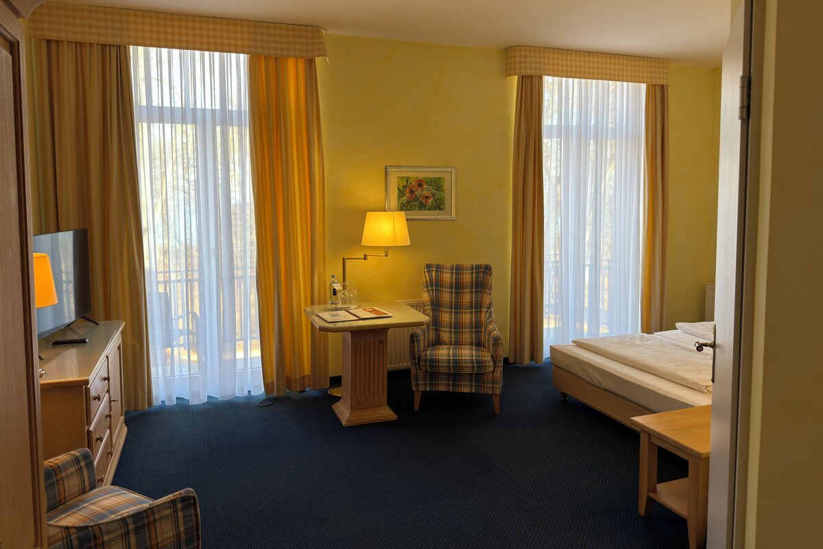Une chambre d’hôtel comprenant un lit, un bureau avec une lampe, une chaise et un téléviseur.