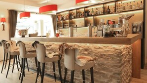 A bar area with a stone counter, bar stools, and a variety of bottles and glasses. - Hotel Wittenbeck by ANS (Wittenbeck)