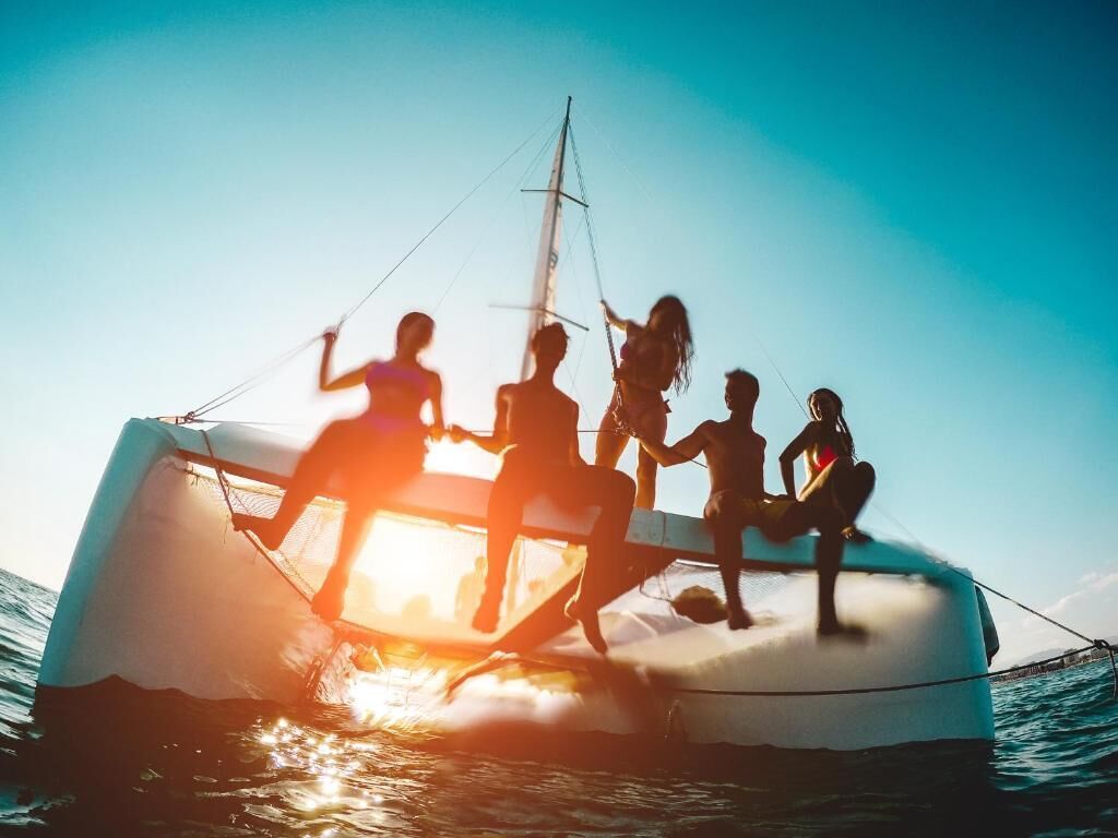 Een zeilboot met mensen aan boord, een heldere lucht en rustig water.