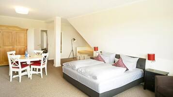 A bedroom with a bed, bedside tables, a desk with chairs, and a wardrobe.