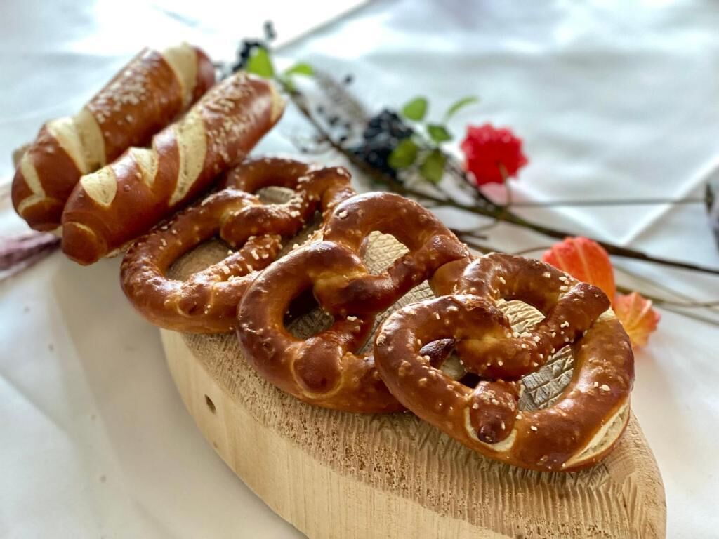 Een houten plank met pretzels en een rolletje gebak.