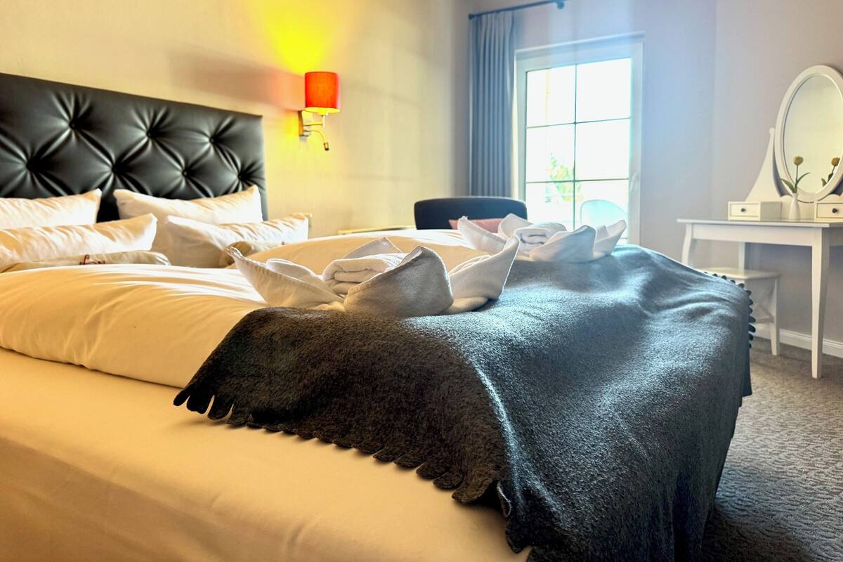 Hotellihuone, jossa on sänky, työpöytä, tuoli, lamppu ja ikkuna.