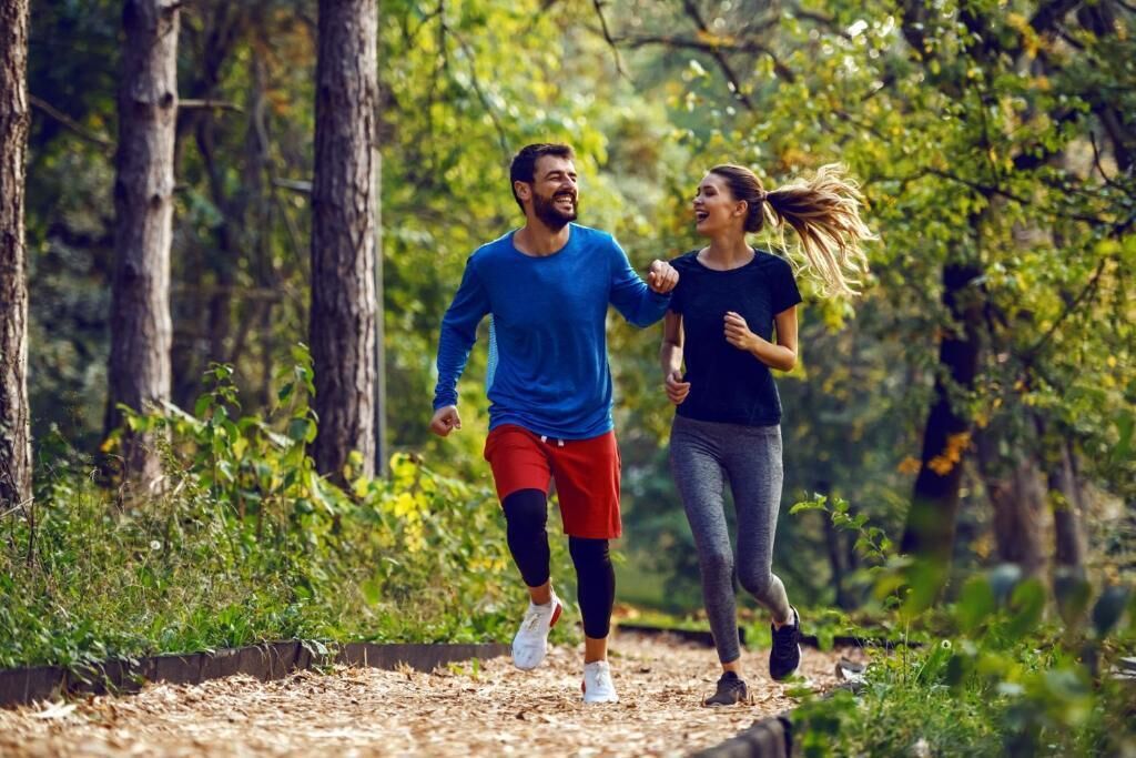 Dos personas trotando por un sendero en el bosque.
