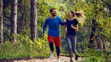 Dos personas trotando por un sendero en el bosque.