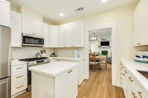 A modern kitchen with white cabinetry, a built-in microwave, and a stove. - Mid-Tide Modern - Easy Walk, Easy Stay, Easy Living (Galveston)