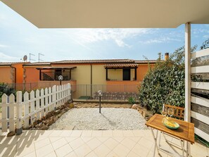 A patio with a white picket fence, a table with a bowl and glasses, and a building with a tiled roof. - Charming Accommodation With Pool in Viddalba (Viddalba)