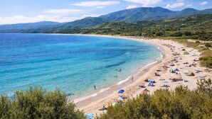 A beach with clear turquoise waters, a sandy shore, and lush green hills in the background. - Charming Accommodation With Pool in Viddalba (Viddalba)