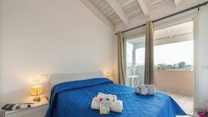 A hotel room with a bed, a nightstand, a lamp, a window with curtains, and a balcony. - Charming Accommodation With Pool in Viddalba (Viddalba)