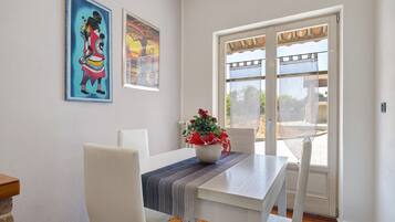 A dining area with a table, chairs, a vase with flowers, and artwork on the wall.