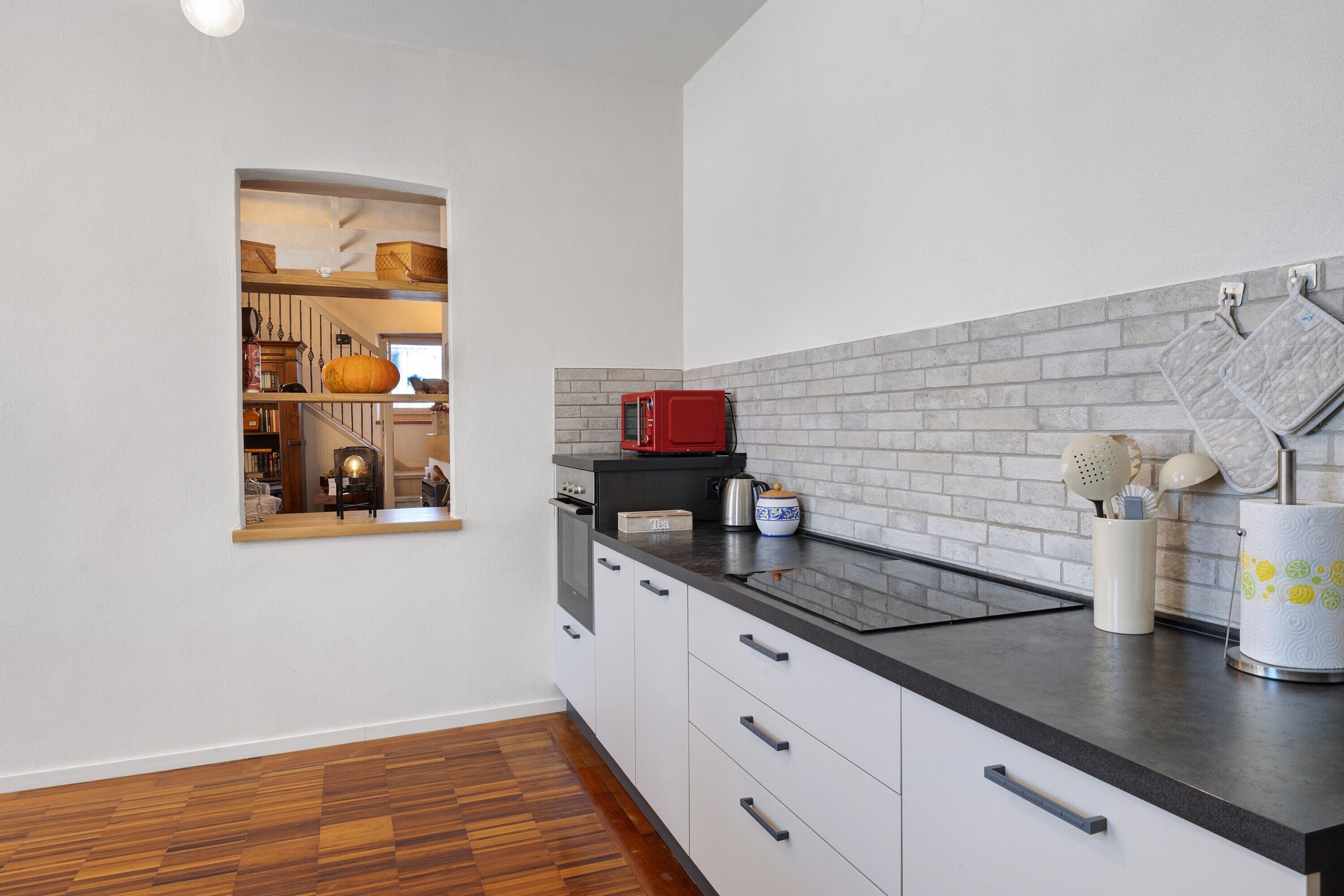 A modern kitchen with a black countertop, white cabinets, and a brick backsplash.
