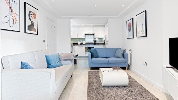 Een moderne woonkamer met een bank, een salontafel en een keuken op de achtergrond.