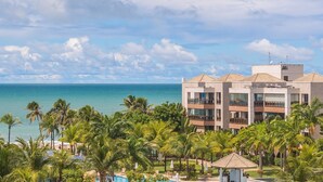 Un hotel moderno con piscina, palmeras y vista al océano.