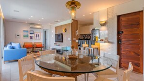 Una sala de estar moderna con una mesa de comedor de vidrio, sillas blancas, un sofá azul y una puerta de madera.