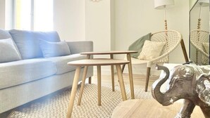 A living room with a sofa, a small wooden table, a wicker chair, and a decorative elephant sculpture. - Quiet apartment near train station and Quimper historic center (Quimper)