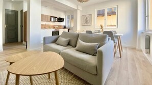A modern living room with a sofa, a round coffee table, and a dining area in the background. - Quiet apartment near train station and Quimper historic center (Quimper)
