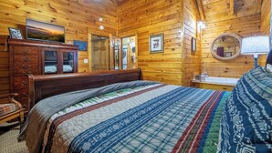 A wooden cabin bedroom with a bed, dresser, and a ceiling fan. - Cozy Cabin Near TOWN! Hot Tub | Fire Pit | Arcade (Sevierville)