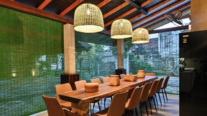 Un comedor moderno con una larga mesa de madera, sillas anaranjadas y tres lámparas colgantes de fibra.