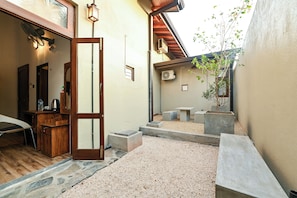 A small courtyard with a wooden bench, a stone pathway, and a potted plant.