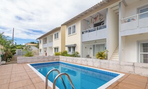 Un immeuble résidentiel doté d’une piscine, d’un balcon et d’une entrée sécurisée.