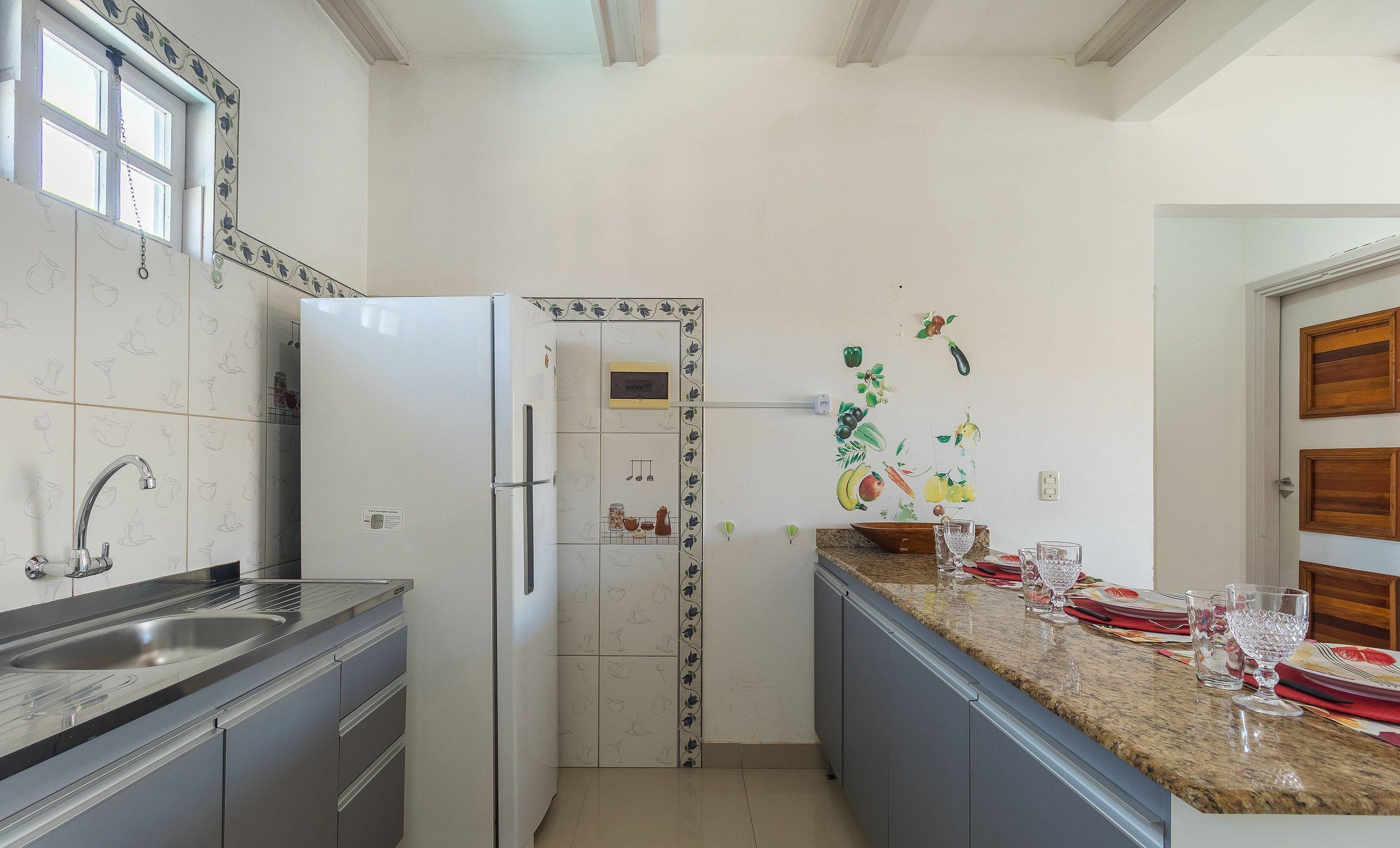 A kitchen with a stainless steel sink, a white refrigerator, and a granite countertop.