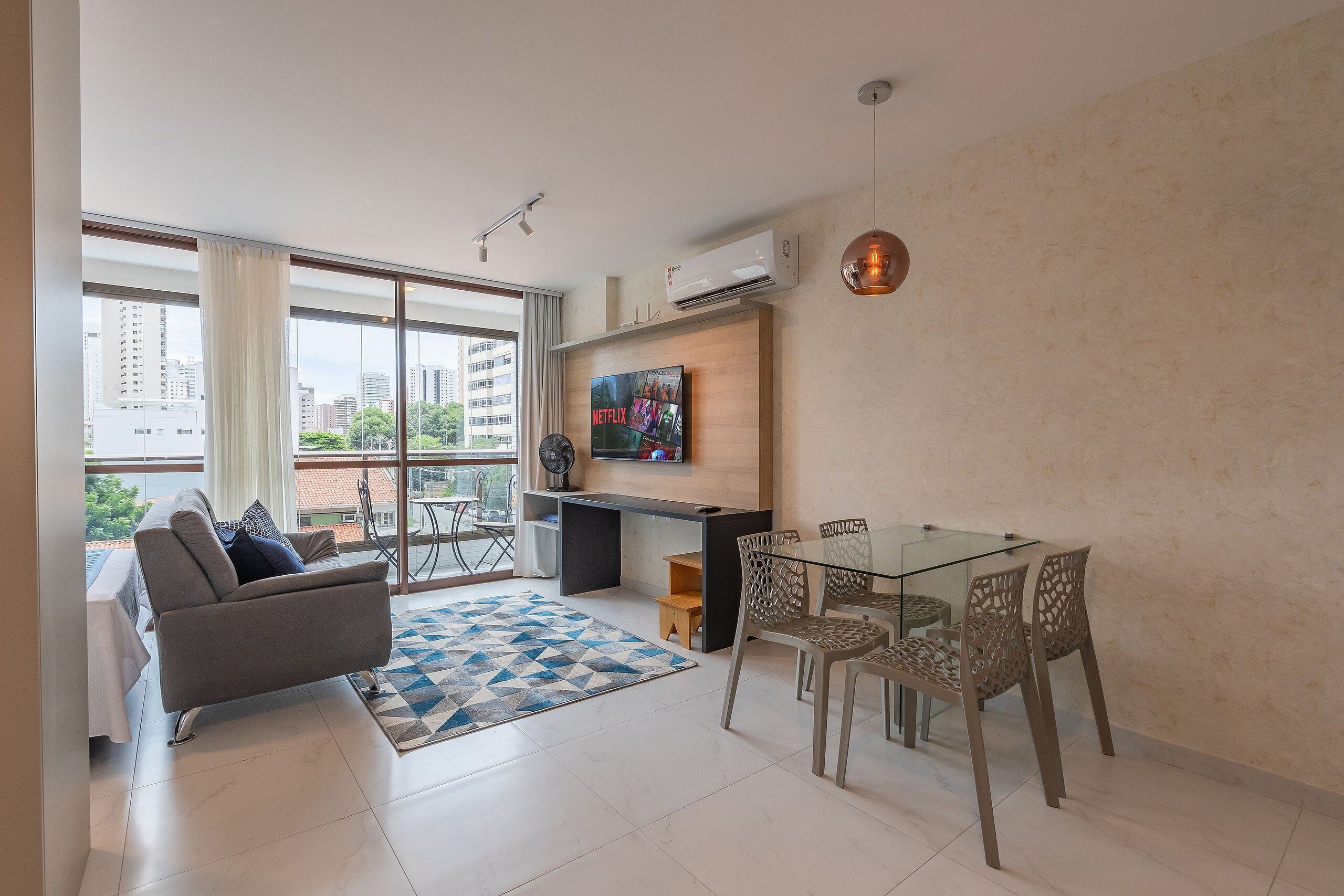 A modern living room with a sofa, coffee table, TV, and dining area.