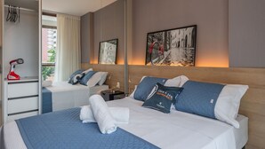 Een hotelkamer met twee bedden, een grote spiegel, een schilderij en een rode haardroger.