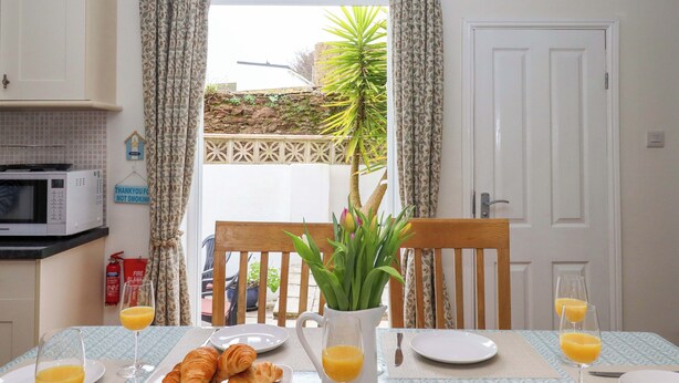 Ein Frühstücksbuffet mit Croissants, Orangensaft und Blick auf einen Garten durch eine Tür.