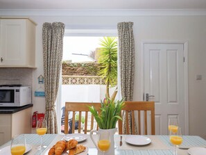 Desayuno con cruasanes, jugo de naranja y vista a un jardín a través de una puerta.