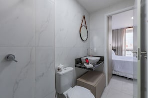 Et moderne badeværelse med toilet, håndvask og bruser.