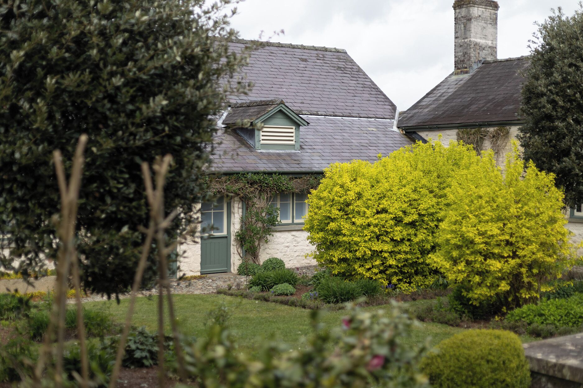A house with a stone facade, a green door, and a chimney.