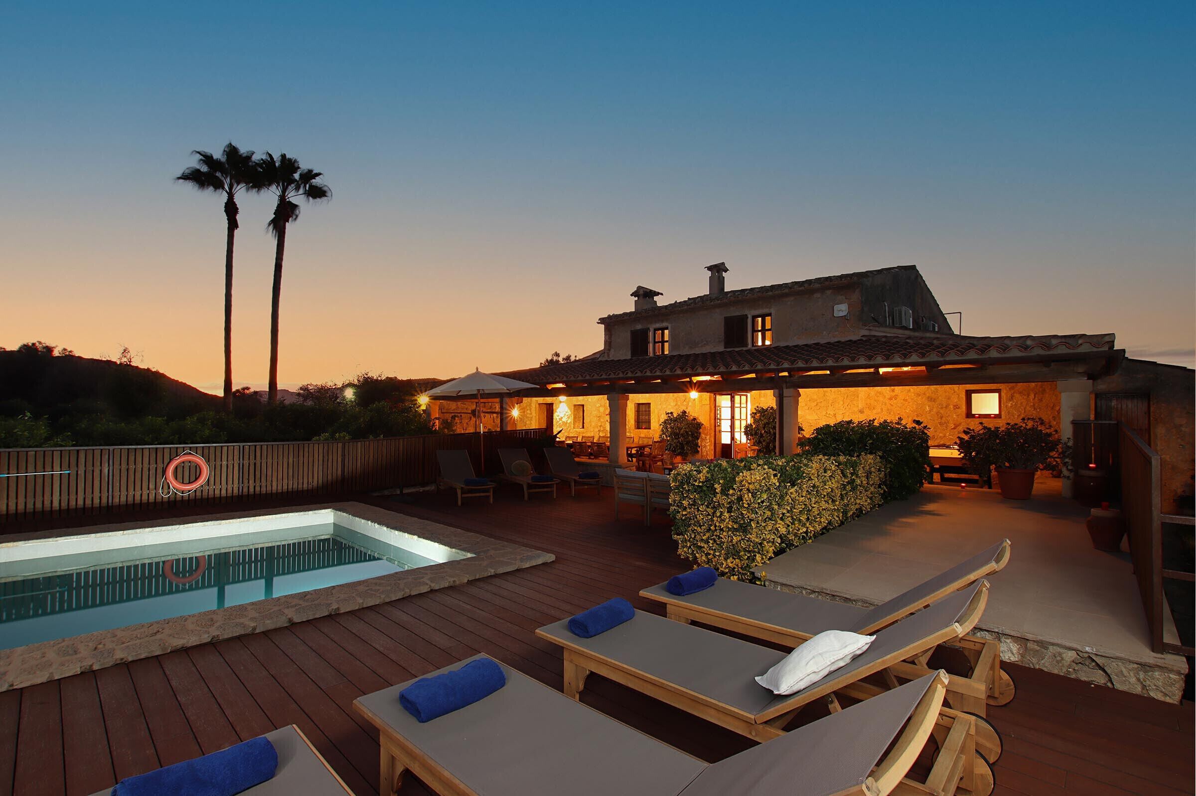 A poolside area with lounge chairs, a swimming pool, and a building with outdoor seating.