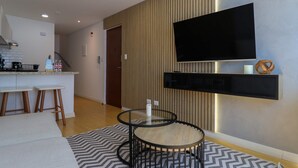 A modern kitchen with a built-in stove, bar stools, and a flat-screen TV mounted on the wall. - w* | Deluxe 1BR Duplex in the Heart of Barranco (Barranco)